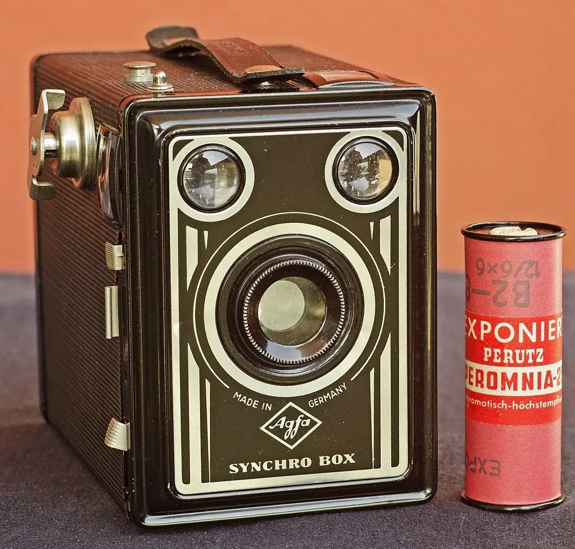 赤いフィルム缶の横に置かれた古いボックスカメラ